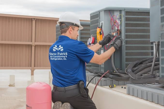 Technician using diagnostic tools on rooftop HVAC equipment